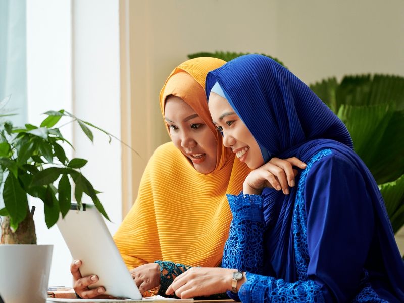 female-friends-discussing-information-tablet-computer