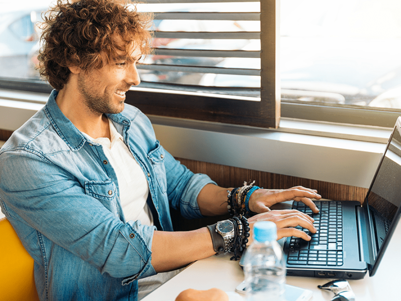 handsome-young-man-using-laptop-while-have-lunch-restaurant-bar