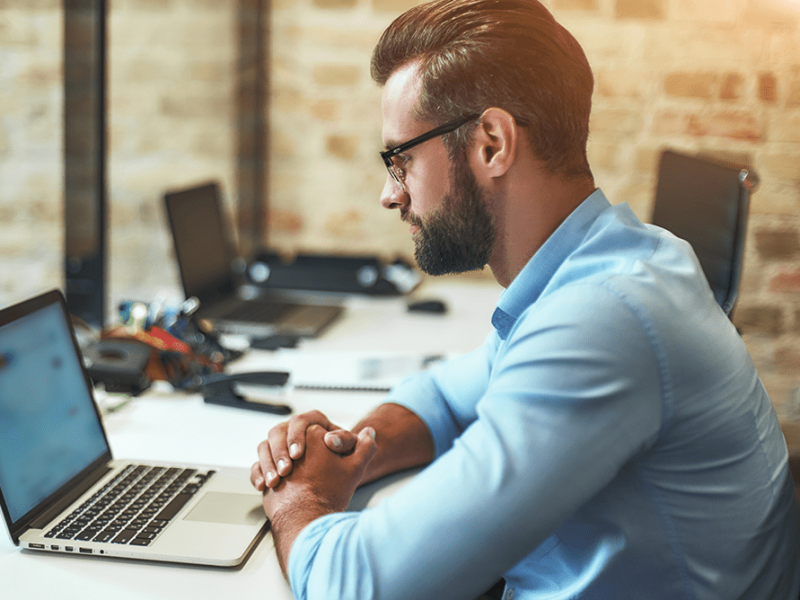 side-view-young-bearded-businessman-eyeglasses-formal-wear-looking-laptop