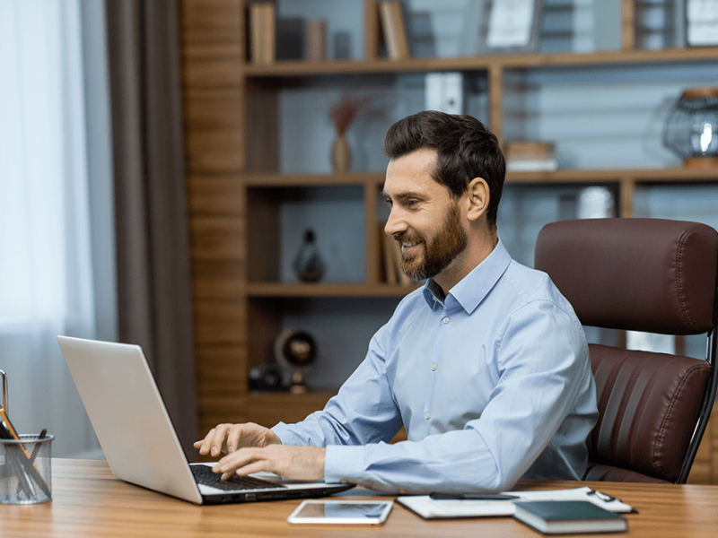 smiling-young-man-is-working-office-sitting-laptop-typing-keyboard
